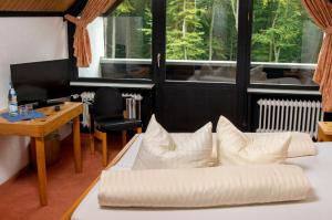 a white couch with pillows in a room with a desk at Landhotel Westerwald in Ehlscheid +30 photos