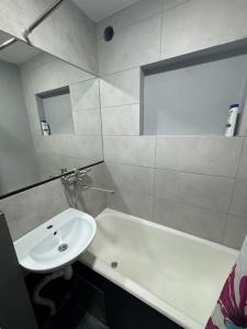 a bathroom with a sink and a tub and a white sink at Aeroport apartament in Chişinău