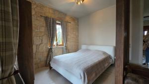 a bedroom with a bed and a stone wall at To Petrino, Stylish Stone House, Elani in Siviri +12 photos