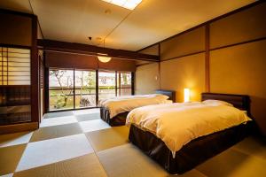 a bedroom with two beds and a large window at Ryoutei Ryokan Yasui in Hikone