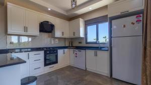 a kitchen with white cabinets and a white refrigerator at SUNSHINE VILLALAR in Belek