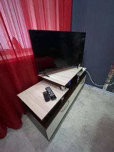a desk with a tv and two remote controls at Сеть BRAUN Сатпаева 40 in Pavlodar