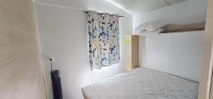 a small bedroom with a bed and a curtain at Bungalow-Mobilhome - Petit prix- Océan -Forêt -Camping 3 étoiles in Bias +46 photos