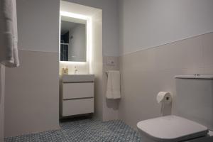 a white bathroom with a toilet and a sink at Apartamentos "El Aljibe" - Parking incluido in Badajoz