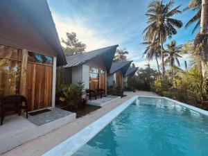 a villa with a swimming pool in front of a house at WADI Hut Siargao in General Luna