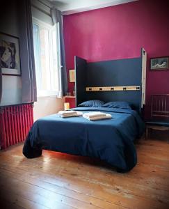 a bedroom with a bed with a purple wall at Love Room LE DONJON BDSM in Bolbec