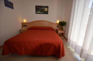 a bedroom with a red bed and two windows at Hotel Tivoli in Lignano Sabbiadoro