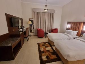 a hotel room with two beds and a television at Vista City Hotel in Dubai
