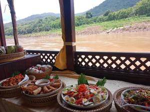 a table with several plates of food and a view of a river at 2 days Mekong cruise package with Mekong Lover Cruise from Houay Xay to Luang Prabang or Mekong cruise from Luang Prabang to Huay Xai - Thailand in Ban Khonkèo +54 photos