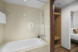 a bathroom with a bath tub and a bedroom at Sivora by Kozystay - Kuningan in Jakarta +21 photos