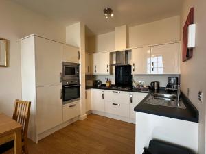 a kitchen with white cabinets and a sink in it at Harbour View in Ilfracombe