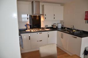 a kitchen with white cabinets and a stove top oven at Harbour View in Ilfracombe +6 photos