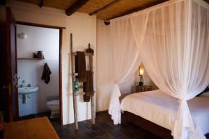 a bedroom with a bed with curtains and a toilet at Karoo Khaya in Prince Albert