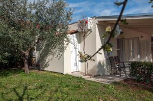 ein kleines weißes Haus mit einer Veranda und einem Stuhl in der Unterkunft Guest House Bulevar in Zadar