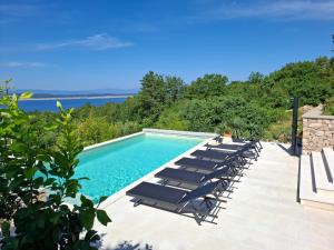 a swimming pool with lounge chairs and the ocean at Villa Belvedere in Crikvenica