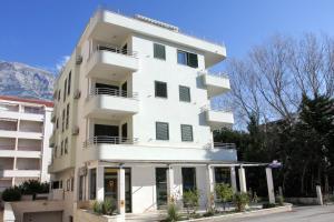 a white apartment building with mountains in the background at Apartments Sumic in Makarska