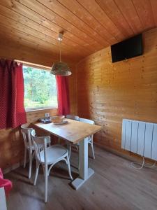 ein Esszimmer mit einem Holztisch und Stühlen in der Unterkunft La Roulotte Authentique au pays de George Sand avec piscine in Mouhers
