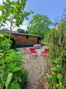 eine Terrasse mit zwei roten Stühlen und einem Tisch in der Unterkunft La Roulotte Authentique au pays de George Sand avec piscine in Mouhers