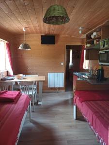 Zimmer mit einer Küche und einem Tisch in einer Hütte in der Unterkunft La Roulotte Authentique au pays de George Sand avec piscine in Mouhers