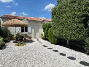 eine Kiesauffahrt mit einem Sonnenschirm und einem Haus in der Unterkunft Maison de ville in Saint-Jean-dʼAngély