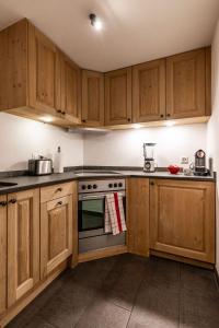 a kitchen with wooden cabinets and a stove top oven at La Ruinette-spacious studio in Verbier centre in Verbier