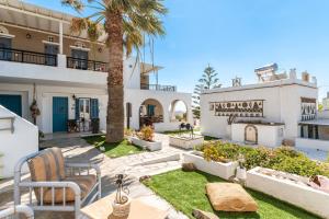 a courtyard with a palm tree and a building at Porto Galini Tinos Myrsini 106 in Agios Ioannis Tinos