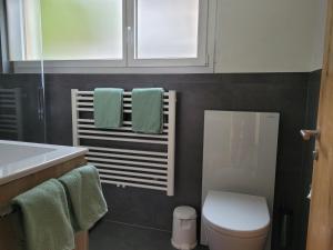 een badkamer met een wit toilet en groene handdoeken bij Haus Perle in Saas-Fee