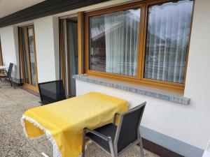 een tafel met een geel tafelkleed op een balkon bij Haus Perle in Saas-Fee