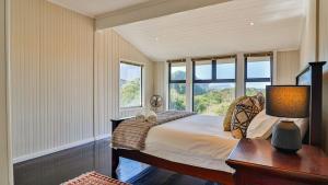a bedroom with a bed with a desk and windows at BluCabana 500m from Main Beach in Bettyʼs Bay