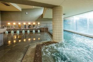 una piscina d'acqua in un edificio con colonne di 神通峡春日温泉ゆーとりあ越中 a Toyama