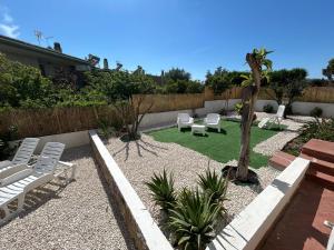 a garden with white chairs and a palm tree at Bed and Breakfast Villa Teis in Quartu SantʼElena