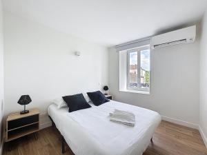 a white bedroom with a bed and a window at Mcosy 5, T2, 4 personnes, clim, proche A75 in Coudes