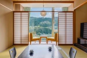 una sala da pranzo con tavolo e sedie e una grande finestra di 神通峡春日温泉ゆーとりあ越中 a Toyama