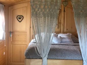 a bedroom with a bed with curtains and a door at Roulotte La Chouette des Granges in Les Salles-Lavauguyon