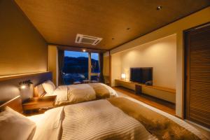 una camera d'albergo con due letti e una televisione di 神通峡春日温泉ゆーとりあ越中 a Toyama Altre 37 foto