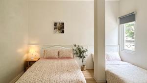 a white bedroom with two beds and a window at LittleBloom homestay in Thôn Trường Giang