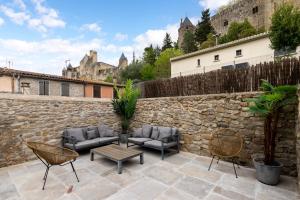 a patio with furniture and a stone wall at Au Pied de la Cité - Terrasse - Climatisation - Wifi in Carcassonne