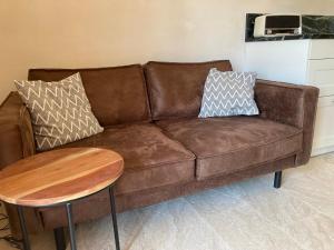 a brown leather couch with pillows and a table at Apartments Mimoza Komiza in Komiža