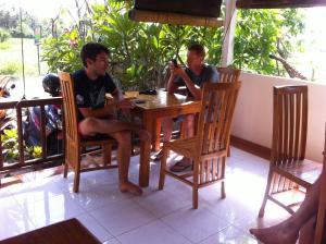 two men sitting at a table on a porch at Mesari Homestay in Amed +41 photos