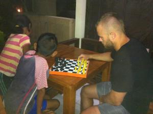 un hombre jugando ajedrez con dos niños en una mesa en Mesari Homestay & Warung, en Amed
