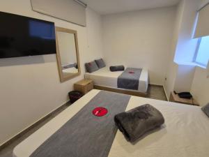 ein Hotelzimmer mit zwei Betten und einem Flachbildfernseher in der Unterkunft Hotel Spa Laureles in Medellín