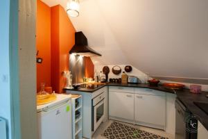 een keuken met oranje muren en witte kasten bij L'Artiste - 60 m - 1 Bedroom in Orléans