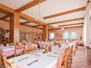 Albergo Alpino da Tullio في أفيو: غرفة طعام بطاولات بيضاء وكراسي خشبية