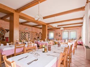 un comedor con mesas blancas y sillas de madera en Albergo Alpino da Tullio, en Avio