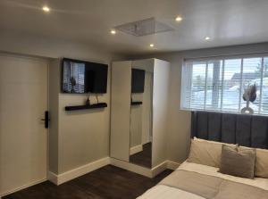 a bedroom with a bed and a tv and a window at Trendy Studio With A Private Garden in Chatham