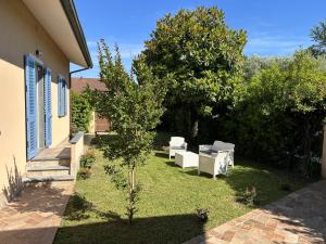 a garden with white chairs and a tree at Tra Arte Amare in Pietrasanta