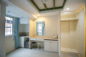 a kitchen with white cabinets and a table and chairs at Skutan Inn Sutthisan Nexus Opal in Bangkok