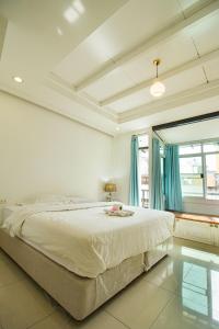 a white bedroom with a large bed with blue curtains at Skutan Inn Sutthisan Nexus Opal in Bangkok +82 photos