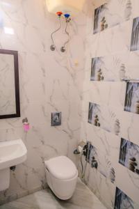a white bathroom with a toilet and a sink at Peepal Tree Residency in New Delhi