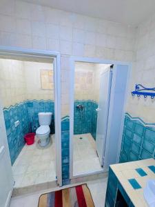 a bathroom with a toilet and a shower with blue tiles at Le petit château Vue sur mer Uniquement les familles in Oualidia +22 photos